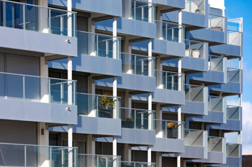 immeuble en bord de mer avec des garde-corps vitrés, vitrage clair, modèle prêt à poser avec doubles poteaux intermédiaires et habillage de la dalle avec un bandeau en aluminium